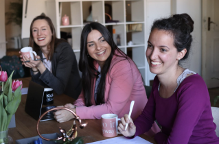 3 Smiling Women Sitting at a Table